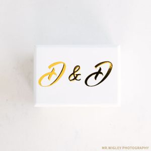 a white double ring box with two initials on the lid